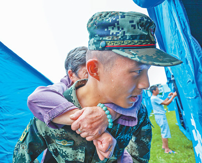 18日，武警官兵背着受灾群众转移。